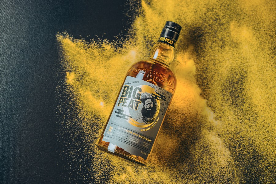A bottle of Big Peat Islay Whisky, with a grey label on a gold background.